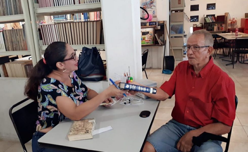 Señor recibiendo un libro en la biblioteca